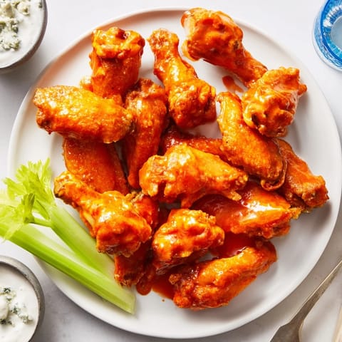 Sizzling fried chicken wings coated in spicy Buffalo sauce served alongside crisp celery and creamy dip.