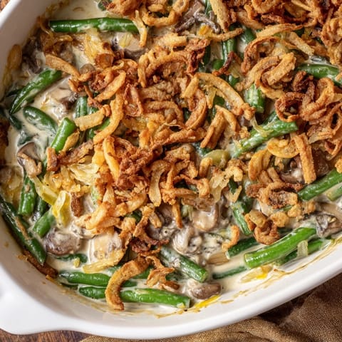Golden-brown crispy onions top a bubbling green bean casserole, ready for a holiday family dinner.
