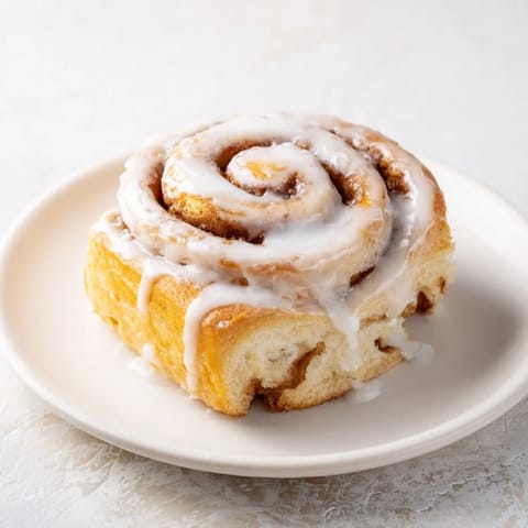 Golden spiraled cinnamon rolls topped with drizzled glaze, placed on a rustic counter for a cozy brunch vibe.
