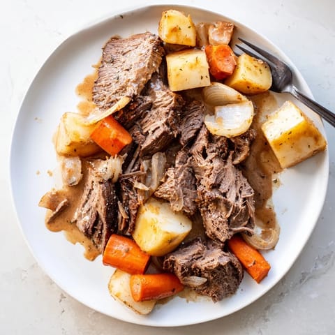 Sliced Beef Pot Roast plated with roasted vegetables and a rich, dark gravy, perfect for Sunday supper.