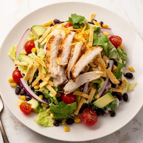 Grilled honey lime chicken slices rest atop a vibrant bed of romaine, corn, and black beans in this Honey Lime Chicken Taco Salad.