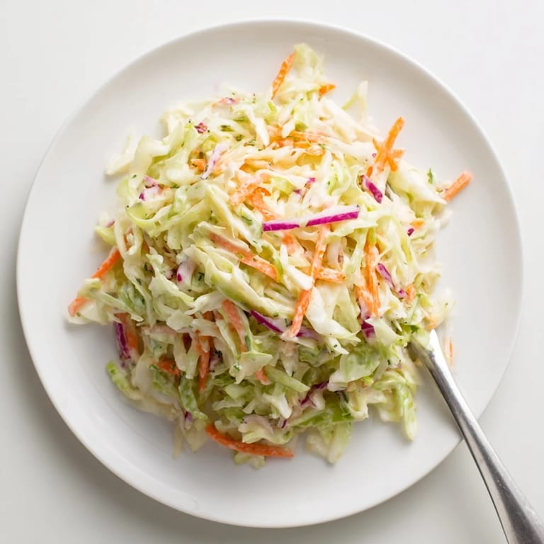 Fresh Coleslaw salad tossed with creamy dressing, served in a rustic bowl with a spoon for barbecue sides.