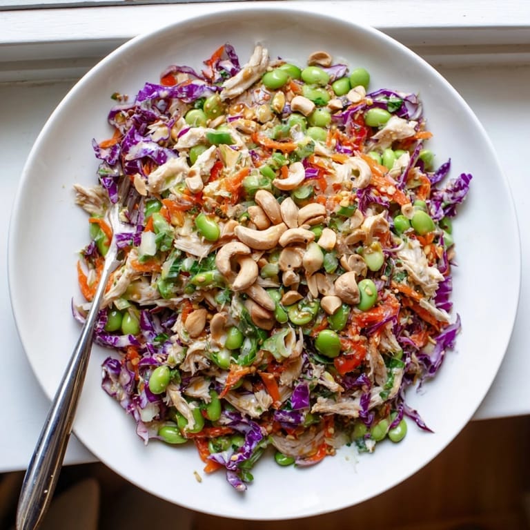 Colorful Edamame Crunch Chicken Salad served in a white bowl, topped with toasted sesame seeds and sliced green onions.