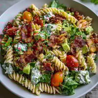 Fresh BLT pasta salad with bacon and avocado, creamy dressing, ripe tomatoes, and crisp lettuce in a hearty bowl.  